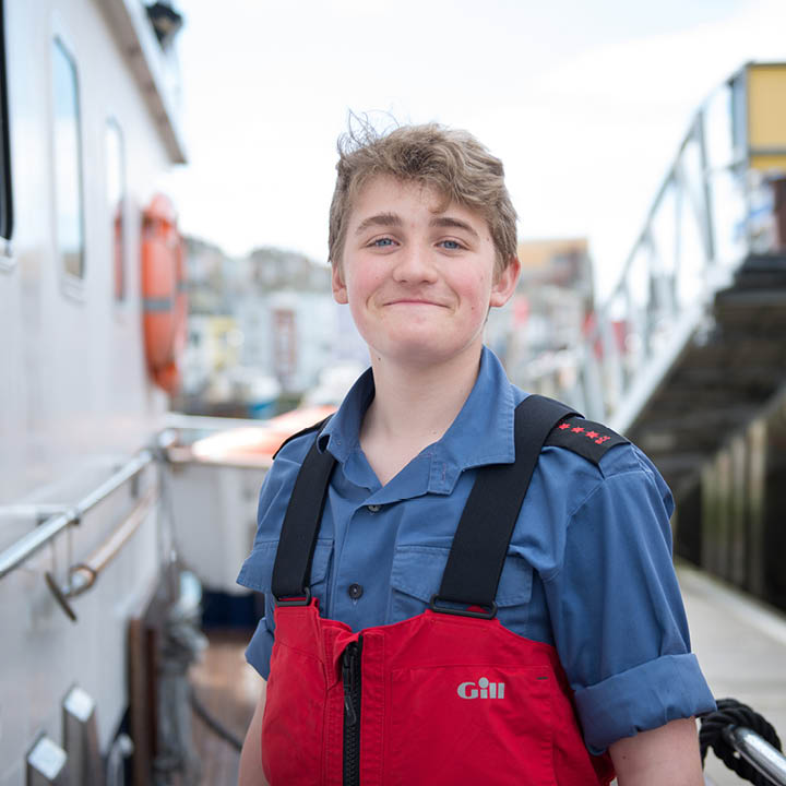 Boy Sea Cadet smiling in safety jacket by a ship